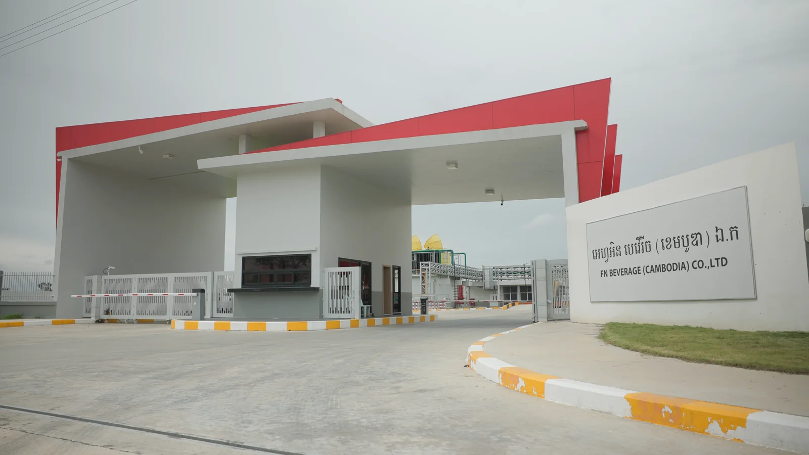 Factory entrance with a red-and-white canopy and FN Beverage (Cambodia) sign